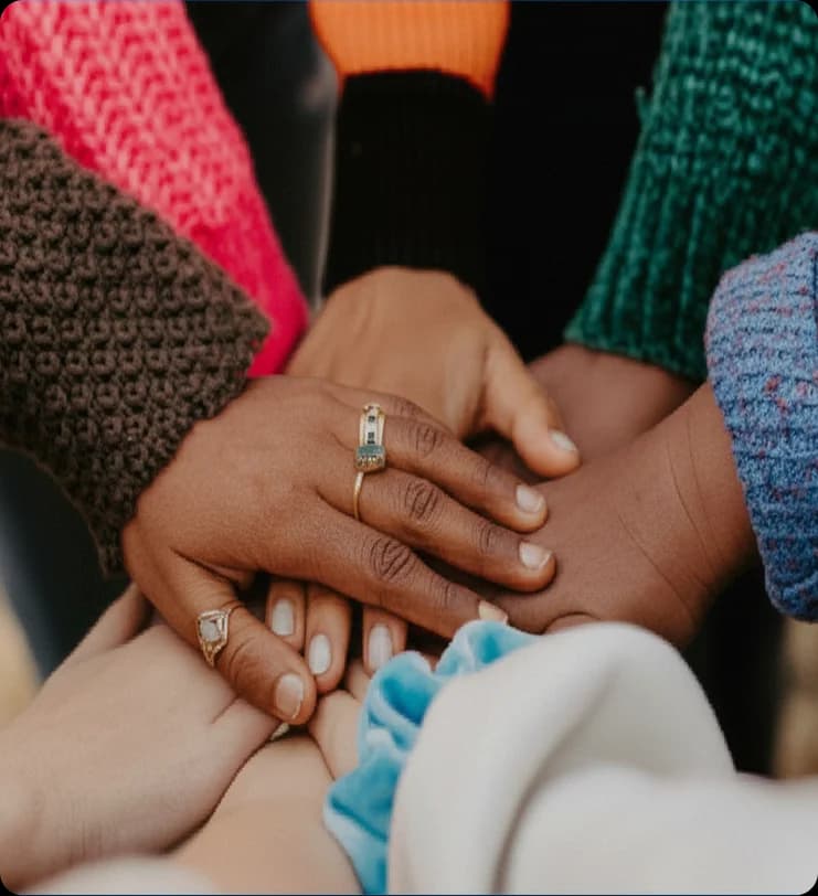 Close-up of diverse hands placed together in support, representing collaboration and humanitarian health care in crisis settings.